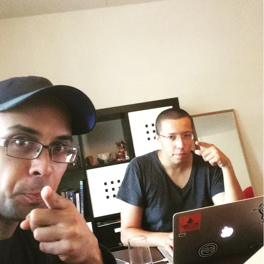 Mike and Vitor working on Happy Plant at a laptop, pointing at the camera